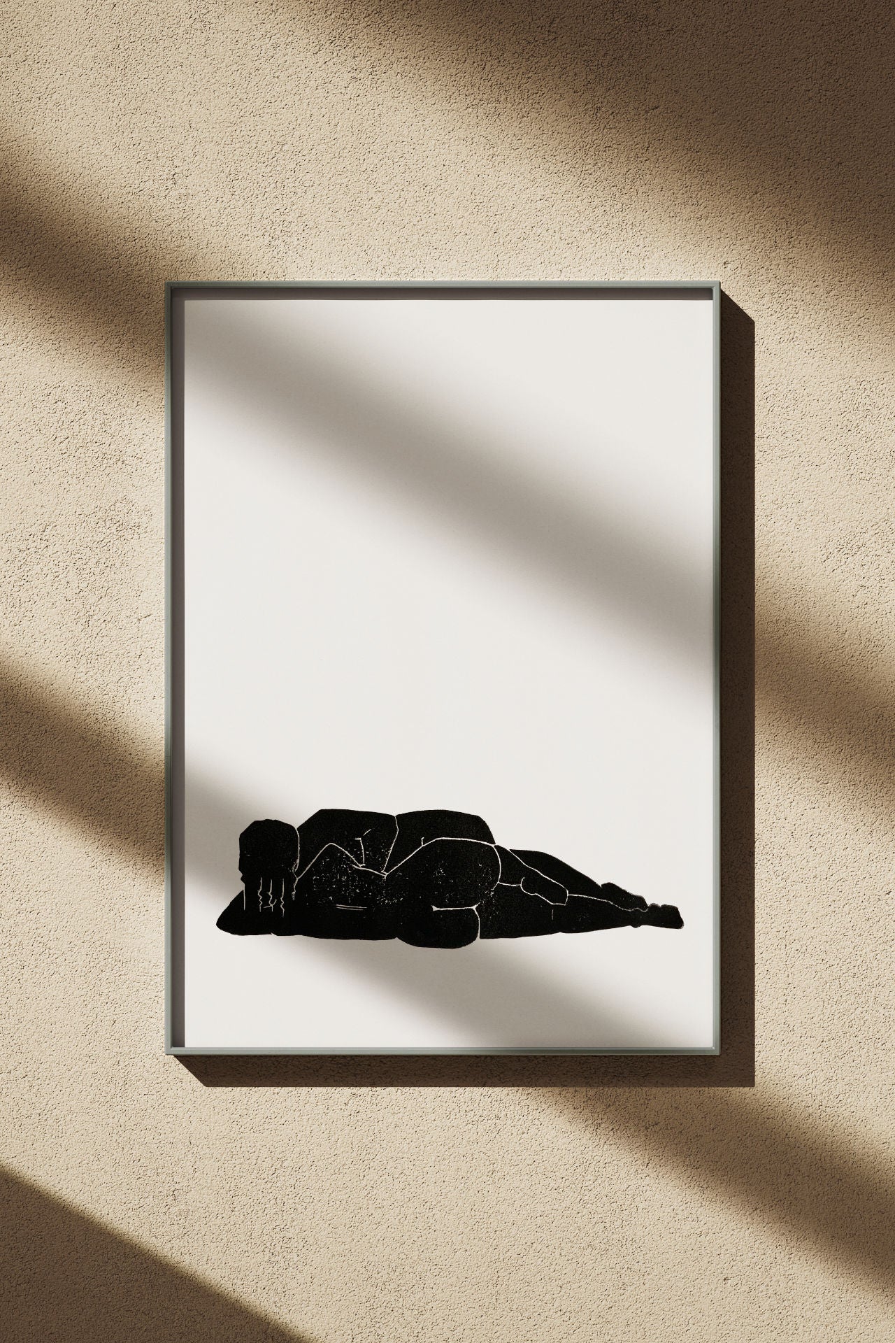 Designstudio Labim: Das Bild zeigt den Linoldruck "Liegen & Lieben". Das Bild hängt an einer Wand im Sonnenschein