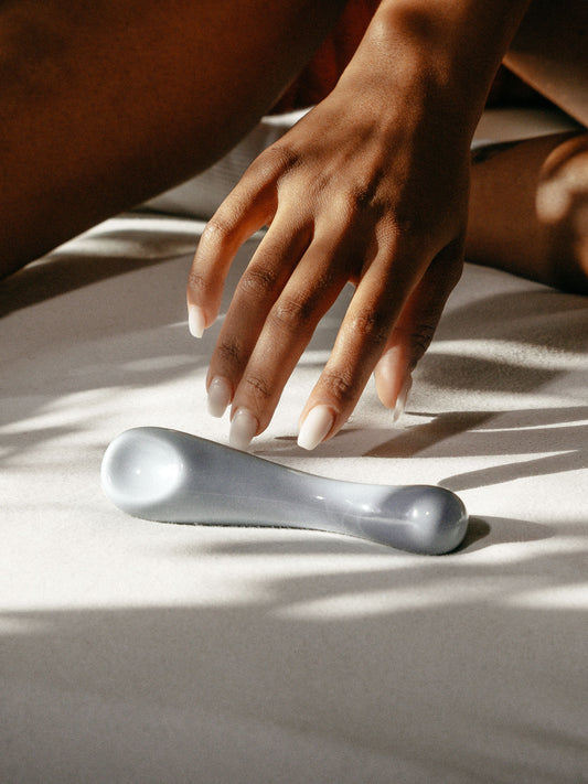 Zu sehen ist der Porzellan-Dildo Clara in Blau von der Marke Labim. Eine Person greift mit der Hand nach Clara. 