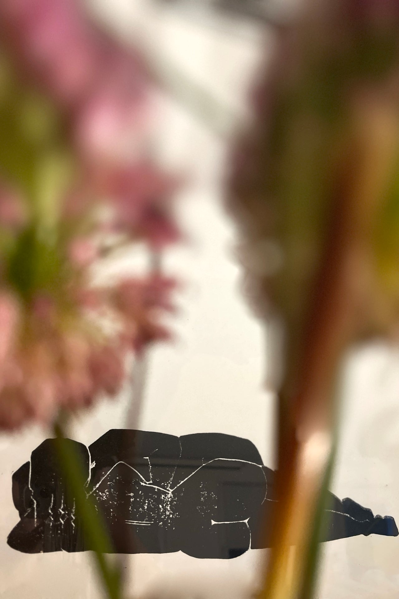 Designstudio Labim: Das Bild zeigt einen Ausschnitt vom Linoldruck "Liegen & Lieben". Im Vordergrund sind verschwommen Blumen zu sehen. 